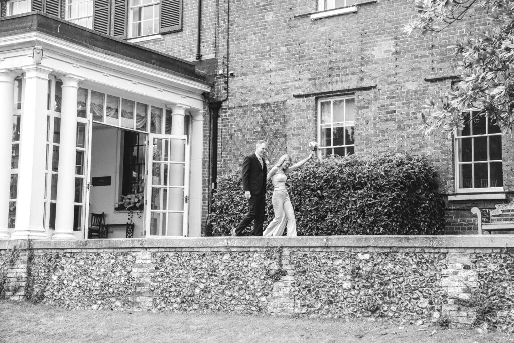black and white photo couple walking out of Leatherhead registry office towards guests