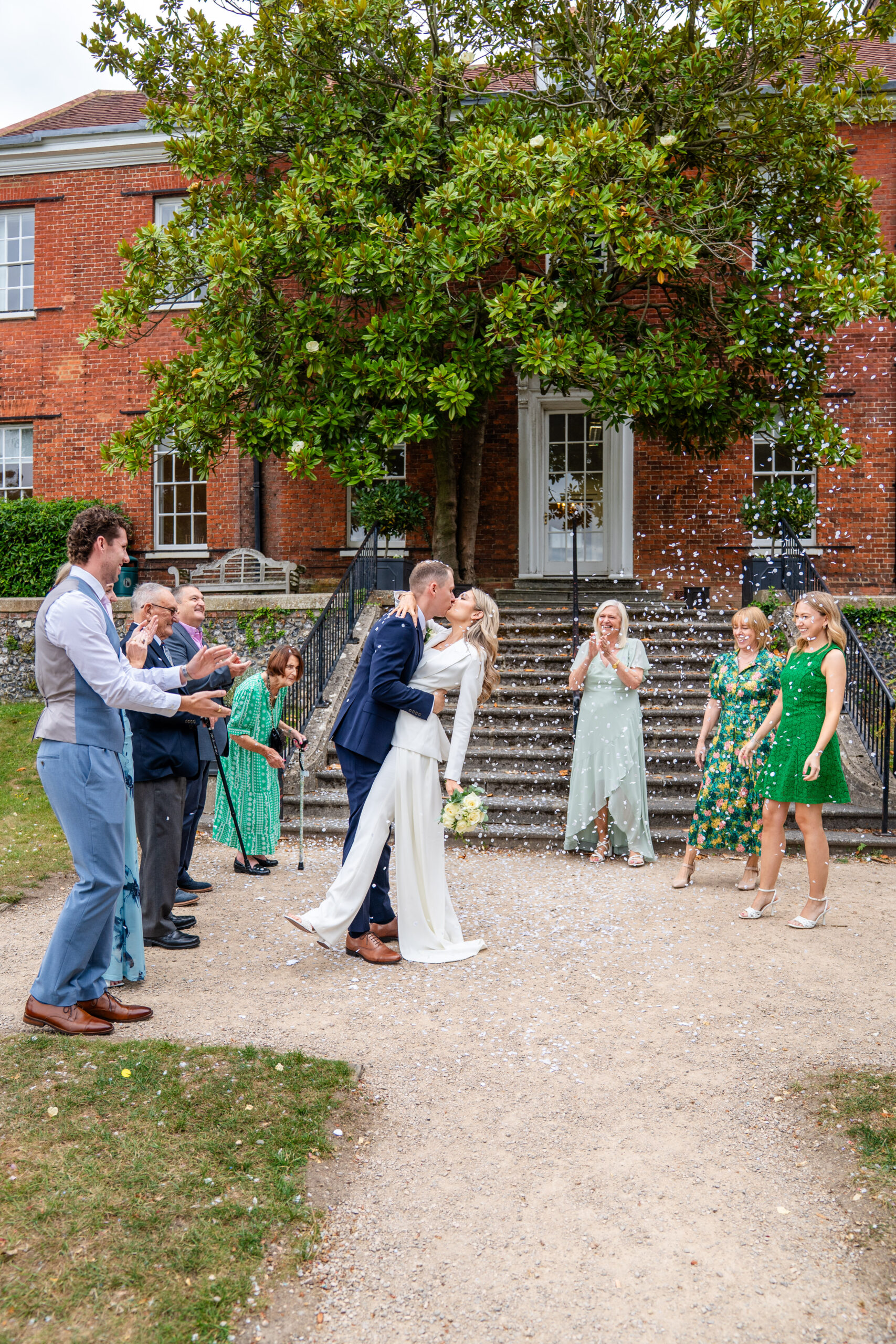 Confetti being thrown on the steps of The Mansion, bride and groom kiss