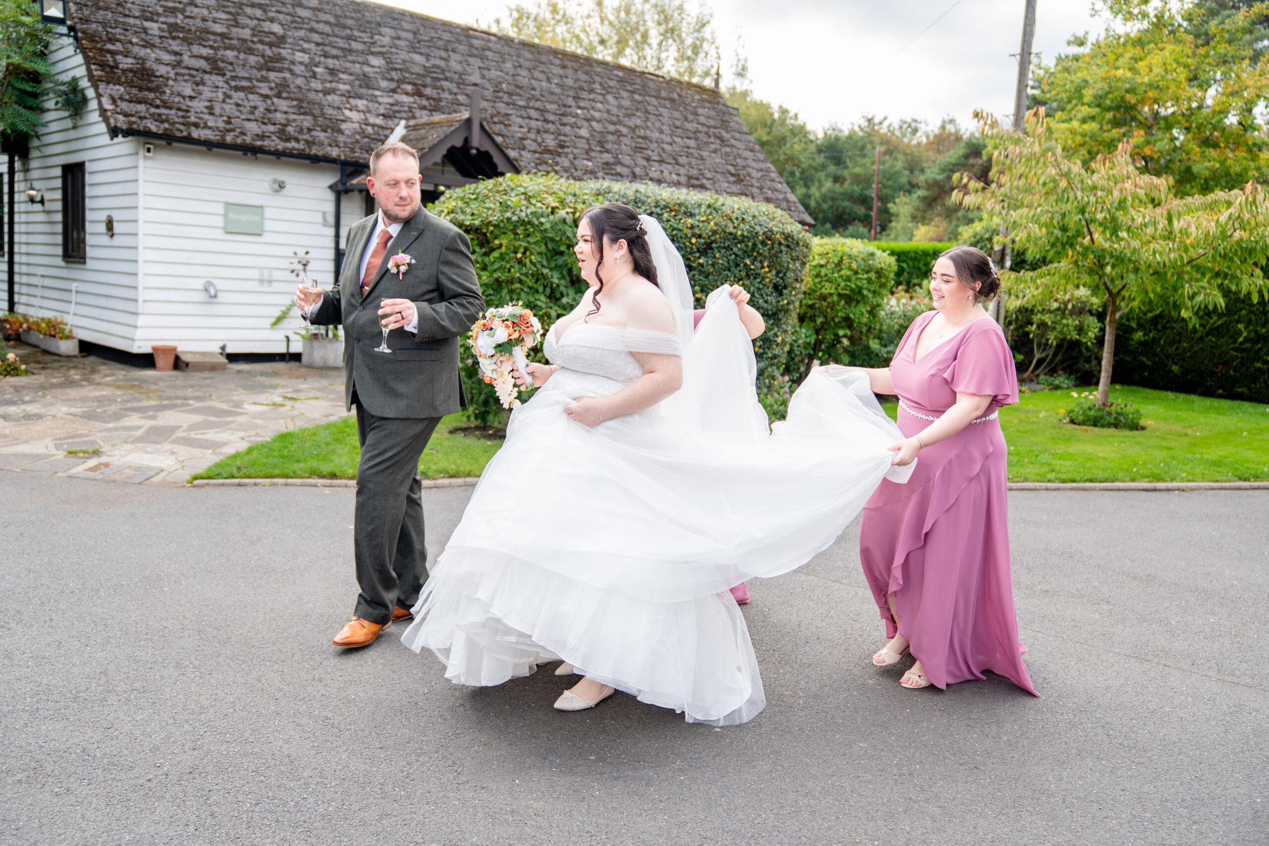 Bridesmaids helping bride outside Oaks farm at the wedding reception 